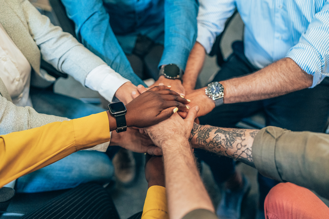 Team of different people joining hands