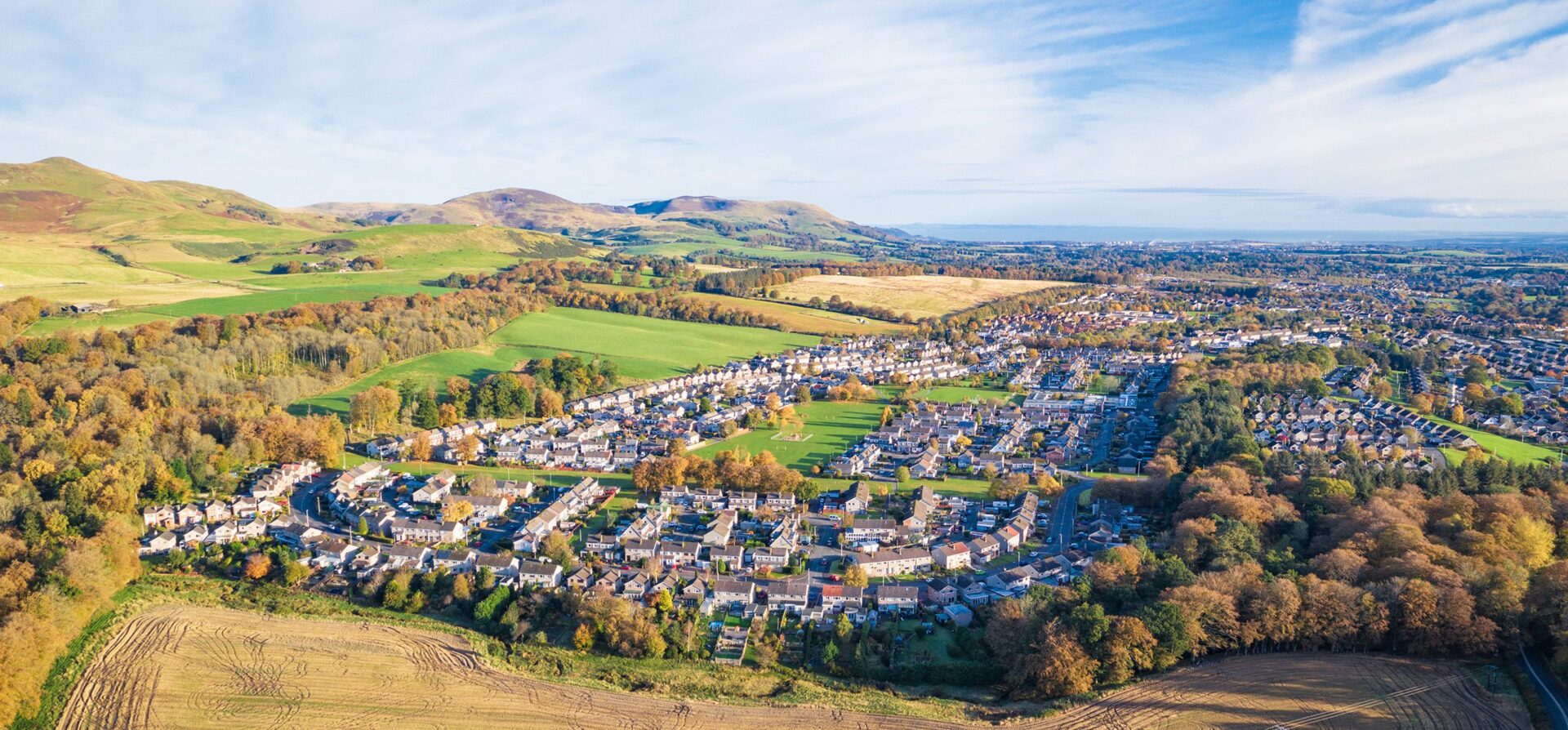 A bird's eye view of an estate with countryside fields on the left